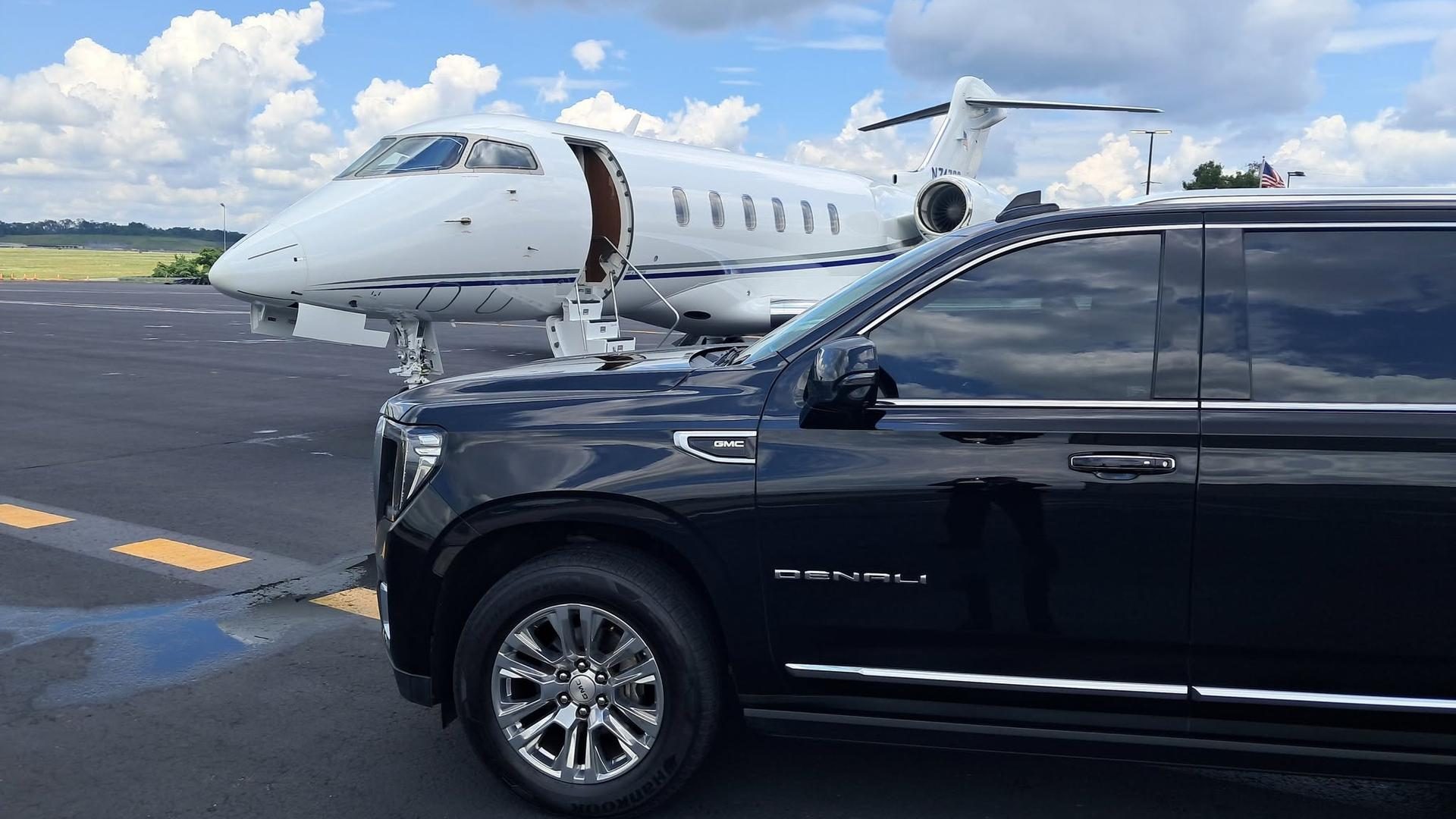 Black luxury SUV beside a private jet at the airport